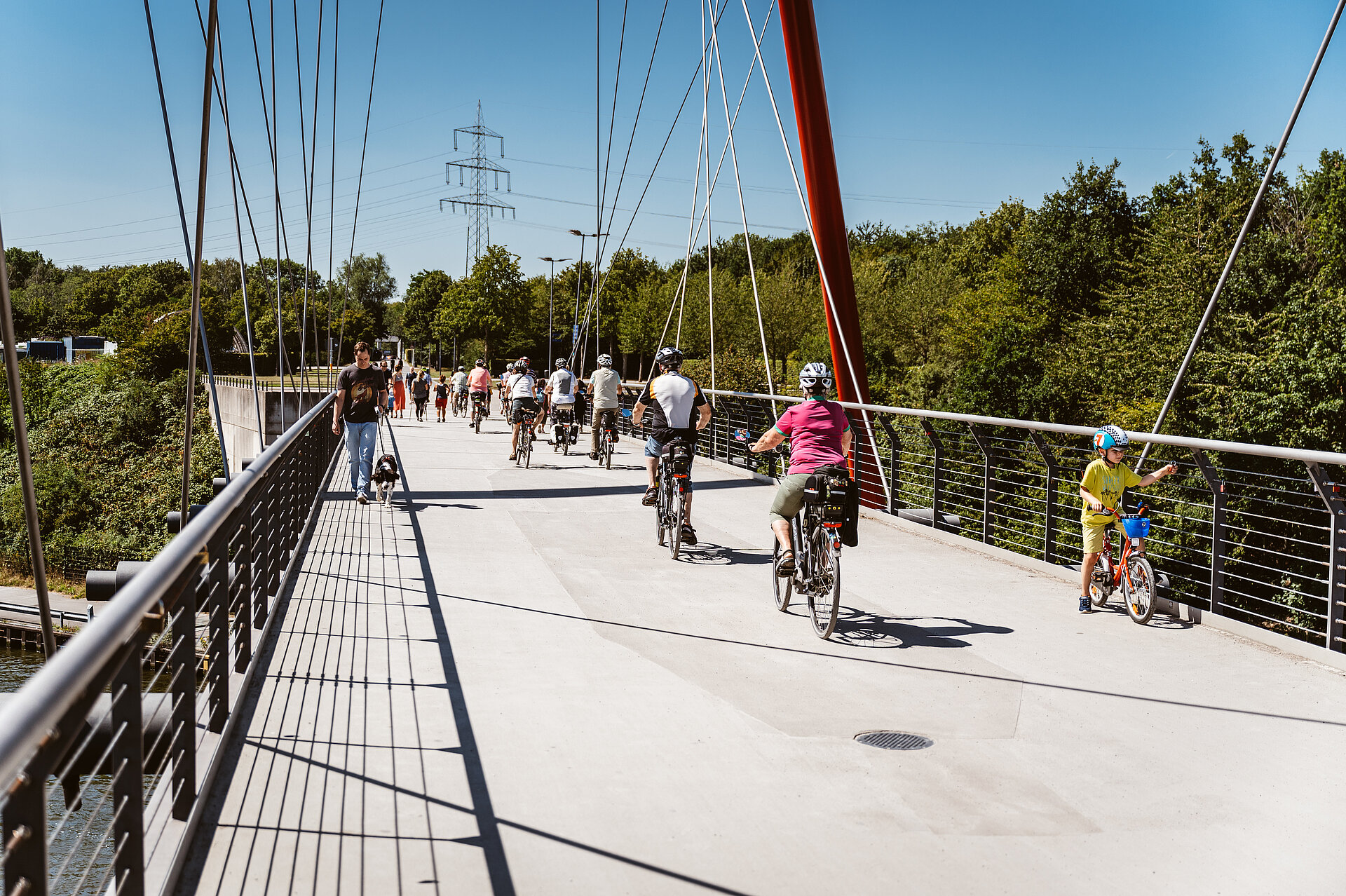Radfahrer auf der roten Doppelbogenbrücke im Nordsternpark Gelsenkirchen.